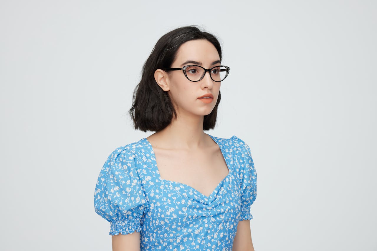 Portrait of a young woman with glasses wearing a blue floral dress, capturing a trendy and elegant look.